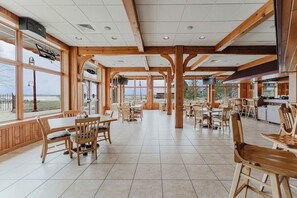 A spacious indoor area with wooden beams, large windows, and multiple seating arrangements. - Wave Pointe Marina and Resort (Sturgeon Bay)