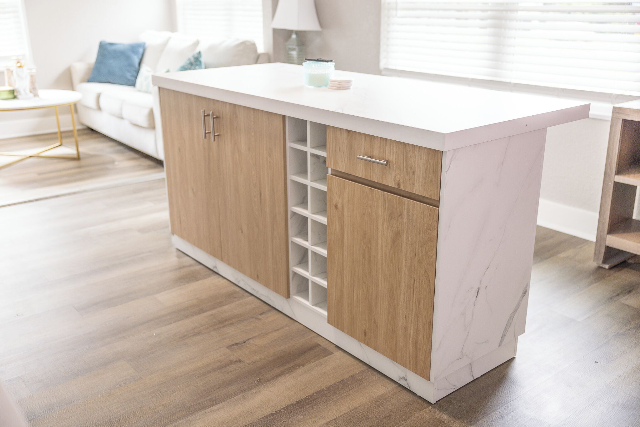 Een moderne keuken met houten kastjes, een marmeren aanrechtblad en een inbouw wijnrek.