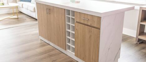 Een moderne keuken met houten kastjes, een marmeren aanrechtblad en een inbouw wijnrek.