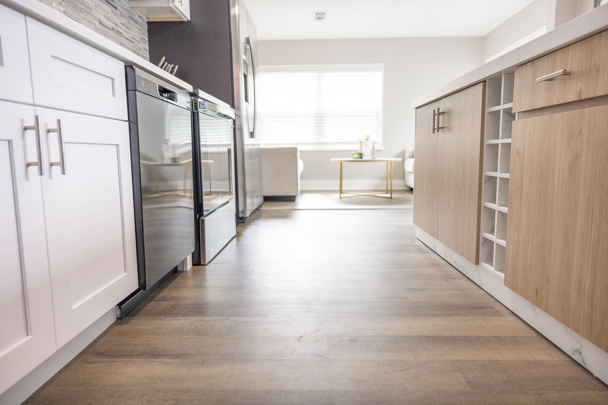 A modern kitchen with white cabinets, a stainless steel refrigerator, and a wooden cabinet.