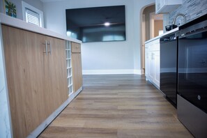 Eine moderne Küche mit Holzschränken, einem Edelstahlkühlschrank und einem an der Wand befestigten Flachbildfernseher.