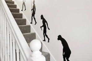 Eine Treppe mit einer einzigartigen Wanddekoration, die Silhouetten von Menschen in verschiedenen Posen zeigt.