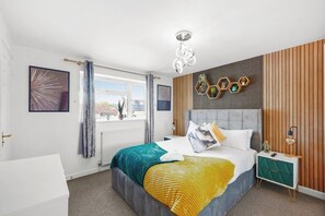 Een moderne slaapkamer met een bed, nachtkastje en uitzicht op het omliggende landschap.