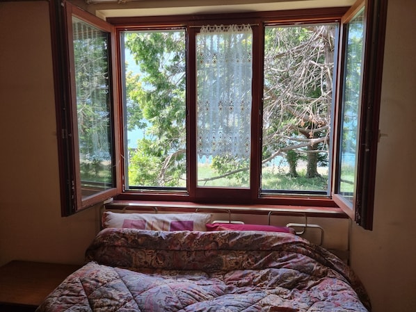 A bedroom with a window overlooking a tree and a view of the outdoors.