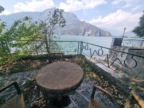 A stone bench with a metal railing overlooking a body of water and mountains.