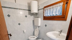 A bathroom with a toilet, bidet, sink, and shower.