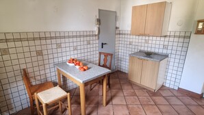 A small kitchen with a tiled backsplash, a wooden table with chairs, and a cabinet.