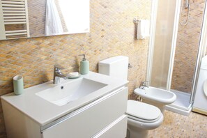 Een badkamer met een wit wastafelmeubel, toilet en douche.