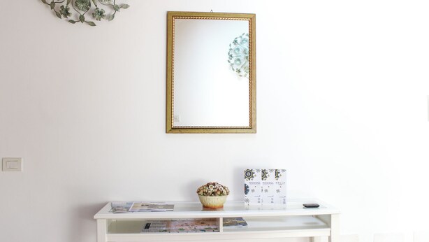 A white console table with a mirror, a bowl of flowers, and a box of magazines. - Family-friendly apartment in Ravenna's historic center near UNESCO monuments (Ravenna)