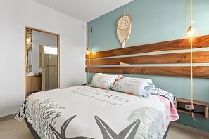 Een slaapkamer met een bed, een houten hoofdbord, een wandlamp en een spiegel.