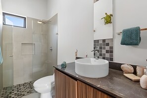 Een moderne badkamer met een glazen douche, een wit wastafelmeubel en een grote spiegel.