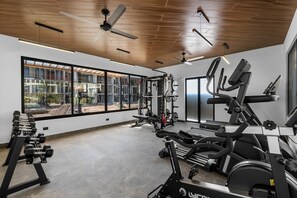Ein Fitnessstudio mit unterschiedlichen Trainingsgeräten, großen Fenstern und einer Holzboden.
