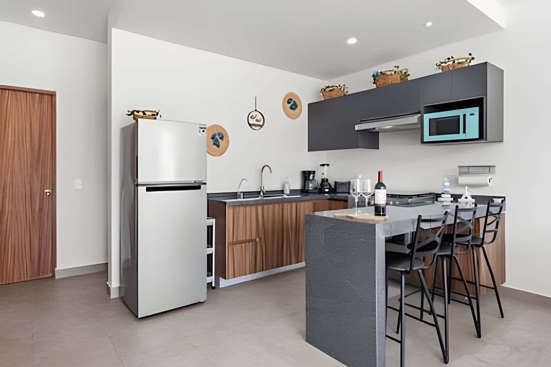 Een moderne keuken met een inbouwkoelkast, een magnetron en een eethoek met een barkruk.