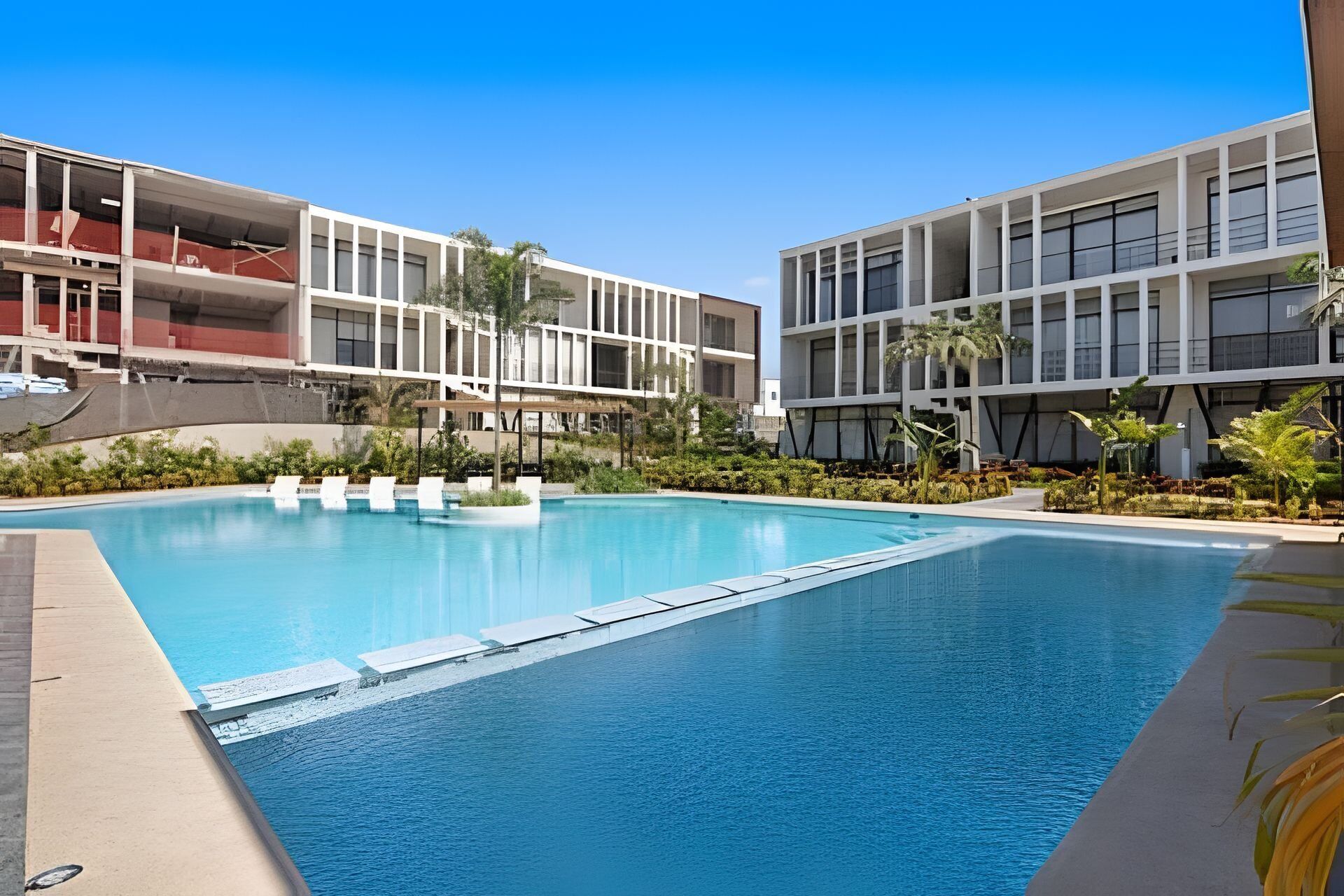 A modern hotel with a swimming pool, outdoor seating, and a landscaped garden.
