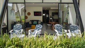 A modern living room with a sofa, chairs, and a dining area visible through large glass doors. - Vrbo Property (Mezcales)