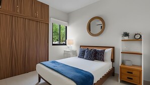 A bedroom with a bed, a bedside table, a wardrobe, a mirror, and a shelf with a clock. - Vrbo Property (Mezcales)
