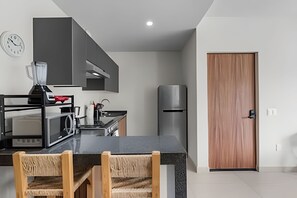 A modern kitchen with a black countertop, stainless steel appliances, and a wooden door. - Ground Floor · 2 Pools · Balcony · 15 min to Beach (Mezcales)