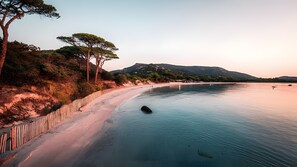 A coastal landscape with a sandy beach, a wooden fence, and a calm sea. - Bed and Breakfast "L'isula" with Mountain View, Wi-Fi, and Air Conditioning (Porto-Vecchio)