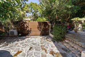 A stone-paved entrance with a metal gate, surrounded by greenery and a stone wall. - Bed and Breakfast "L'isula" with Mountain View, Wi-Fi, and Air Conditioning (Porto-Vecchio)