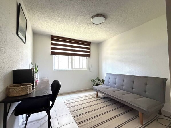 A living room with a sofa, a dining table with chairs, a window with blinds, and a ceiling light. - Vrbo Property (Ciudad de México)
