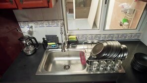 A kitchen with a stainless steel sink, a coffee maker, and a dish rack with plates and glasses. - Apartment near Benito Juárez Airport (Ciudad de México)