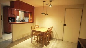 A compact kitchen with wooden cabinets, a dining table with chairs, and pendant lighting. - Vrbo Property (Ciudad de México)