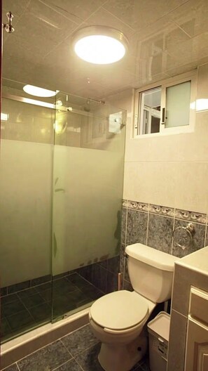 A bathroom with a glass-enclosed shower, a toilet, and a sink. - Vrbo Property (Ciudad de México)