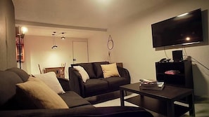 A living room with a sofa, a coffee table, a flat-screen TV, and a bookshelf. - Apartment near Benito Juárez Airport (Ciudad de México)