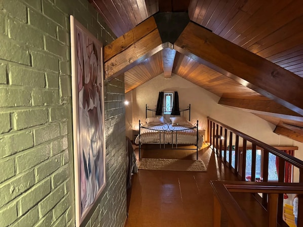 A bedroom with a sloped ceiling, a bed, a window, and a staircase leading to another level. - Homerez - Studio Hamois (Hamois)