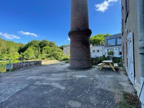 A large brick chimney, a paved area, and a building with a balcony. - New riverside cottage with private terrace (Marboué)