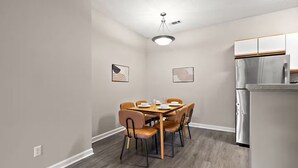 Une cuisine compacte comprenant une table et des chaises, un réfrigérateur et deux luminaires fixés au mur.