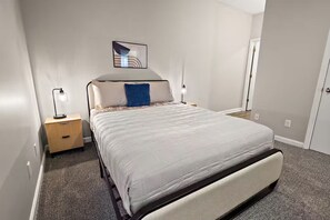 Ein Schlafzimmer mit einem Bett, Nachttischen, einem Wandbild und einer Tür.