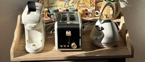 A wooden table with a rustic design, a vintage toaster, a white electric kettle, and a box labeled 'Le Coq en Pointe.'