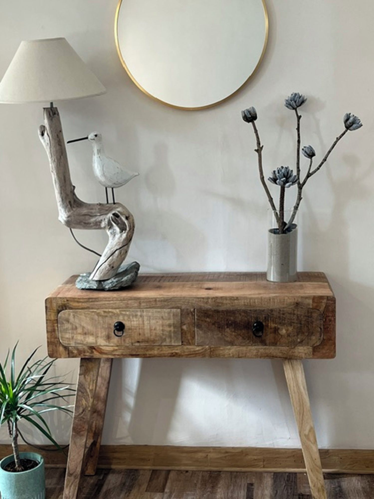 A wooden console table with a lamp and decorative items.