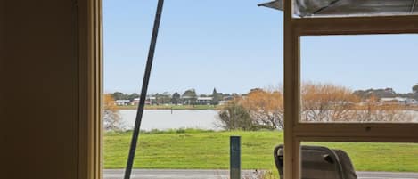 A room with a window overlooking a body of water and a grassy area.