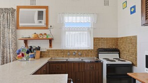 Cuina amb fogó, rentapelats i armaris de fusta.