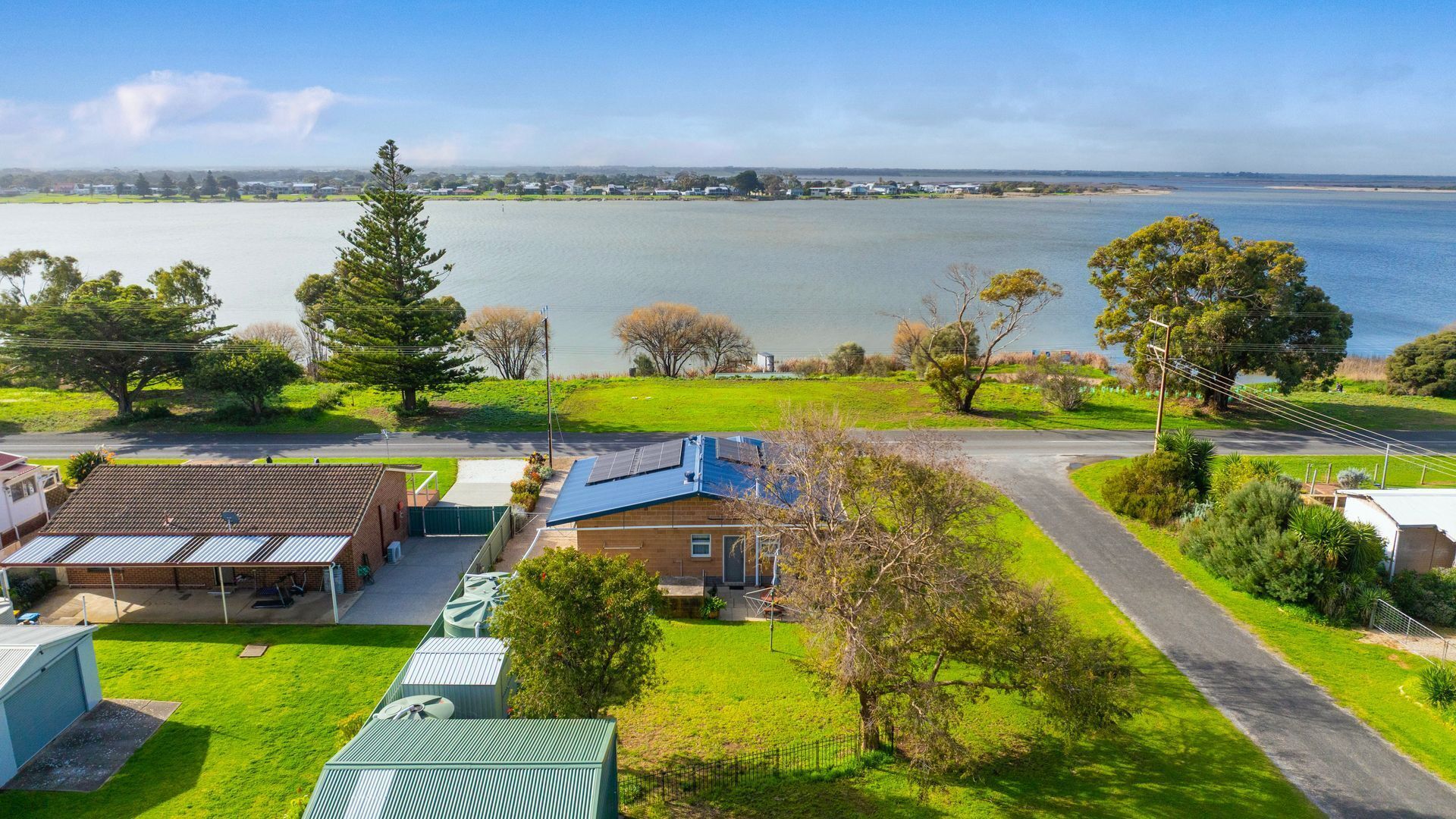A residential area with houses, a road, and a body of water in the background.