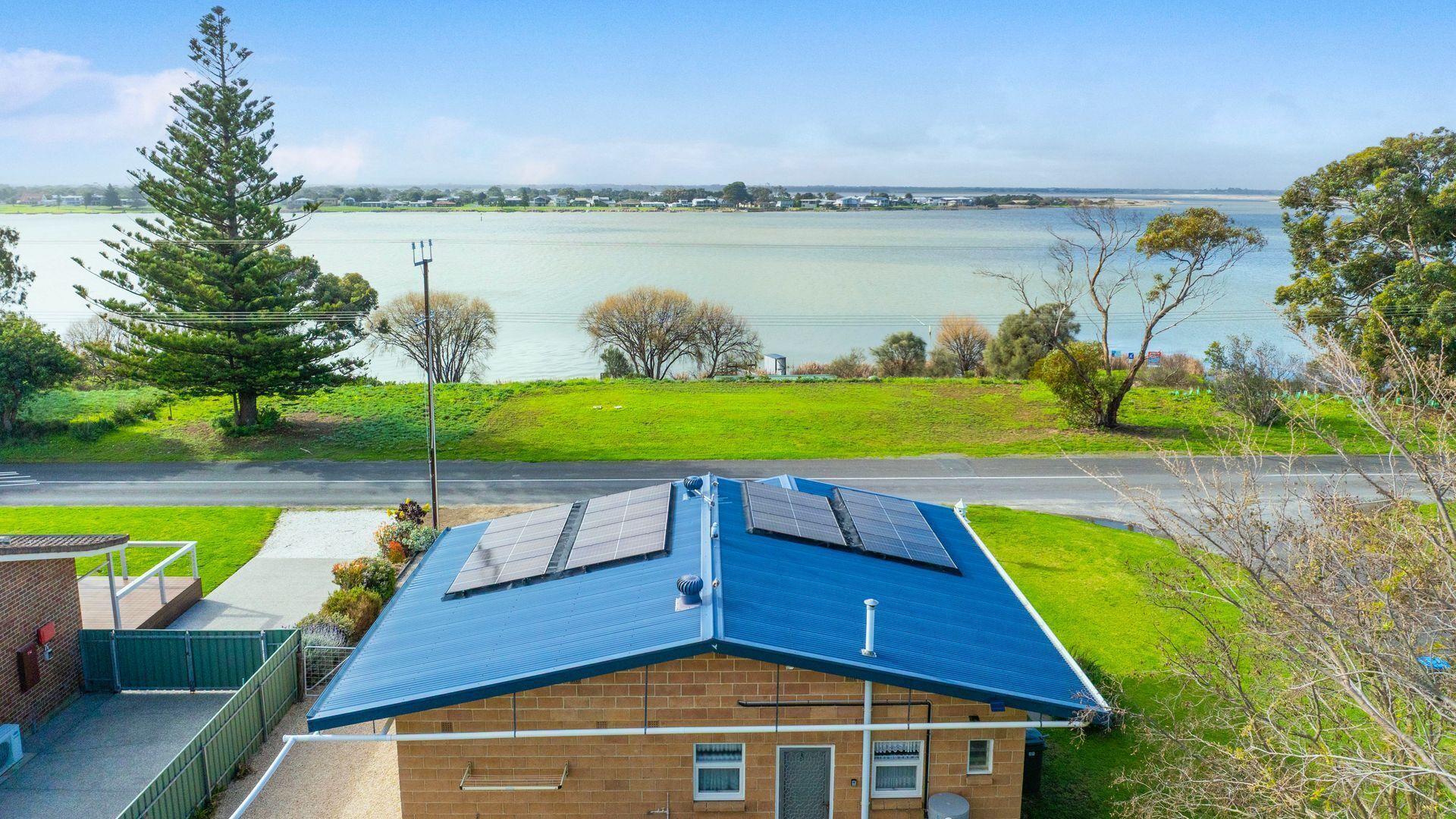 A residential building with a blue roof, solar panels, and a view of a lake.