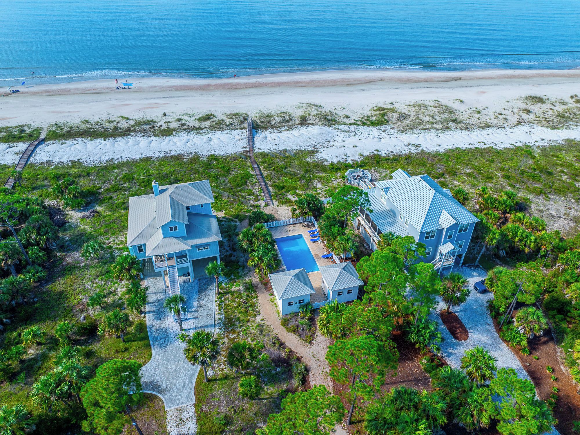 A coastal property with two main buildings, a swimming pool, and a beach view.
