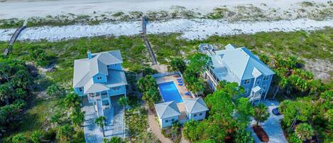 A coastal property with two main buildings, a swimming pool, and a beach view.