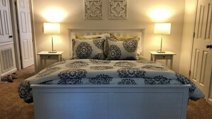 A bedroom with a white bed, two bedside lamps, and decorative wall art. - Hidden Gem! 106 Windstone (Oxford)