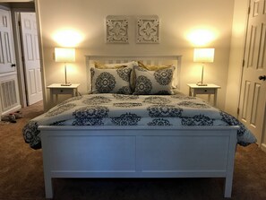A bedroom with a white bed, two bedside lamps, and decorative wall art. - Hidden Gem! 106 Windstone (Oxford)