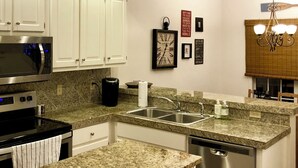 A modern kitchen with white cabinets, granite countertops, stainless steel appliances, and recessed ceiling lights. - Hidden Gem! 106 Windstone (Oxford)