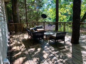 A wooden deck with outdoor furniture, including two chairs and a table, surrounded by trees. - Hidden Gem! 106 Windstone (Oxford)