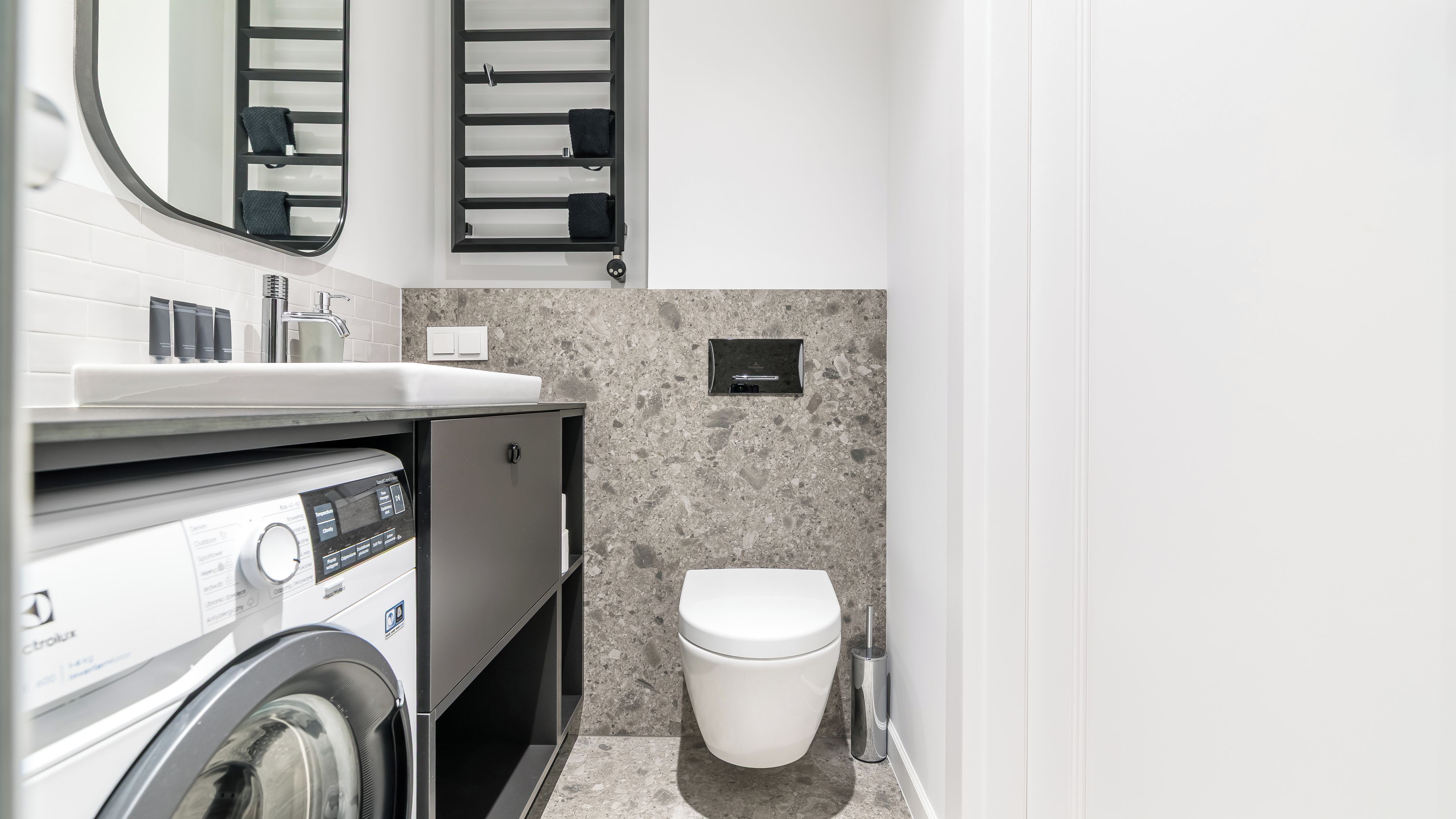 A compact bathroom with a washing machine, a sink, a toilet, and a towel rack.