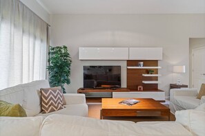 A modern living room with a sofa set, a coffee table, a TV, and built-in shelving. - 5BR home with 5 baths at Windsor Hills (Kissimmee)