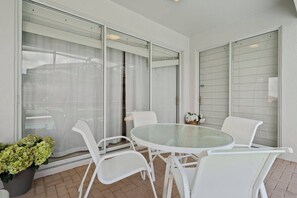 A patio with a glass table and white chairs, a potted plant, and a sliding glass door. - 5BR home with 5 baths at Windsor Hills (Kissimmee)