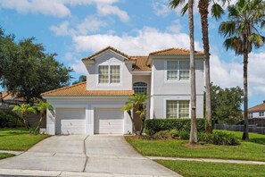 A two-story house with a tiled roof, a garage, and a well-maintained lawn. - 5BR home with 5 baths at Windsor Hills (Kissimmee)