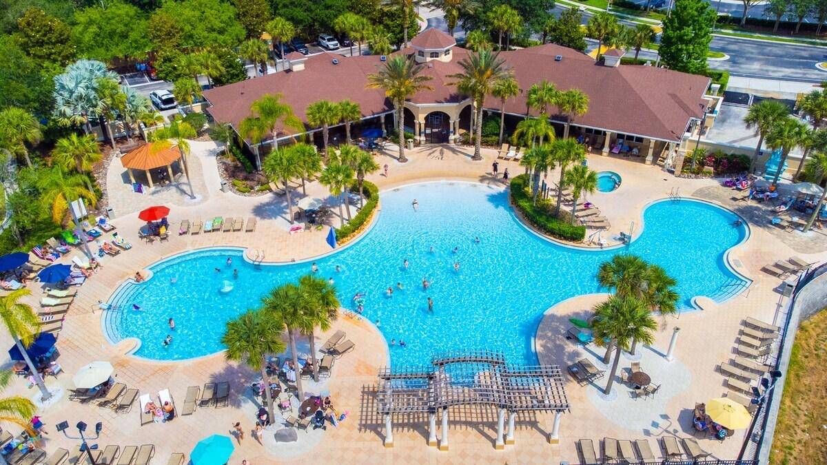 Una amplia piscina al aire libre con varias pistas, rodeada de sillones y sombrillas.