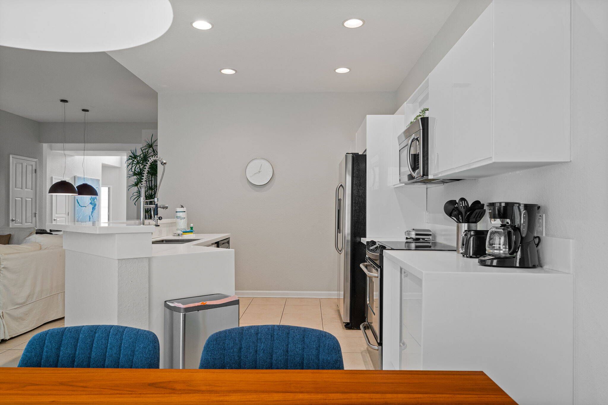 A modern kitchen with white cabinetry, a built-in oven, and a coffee maker.
